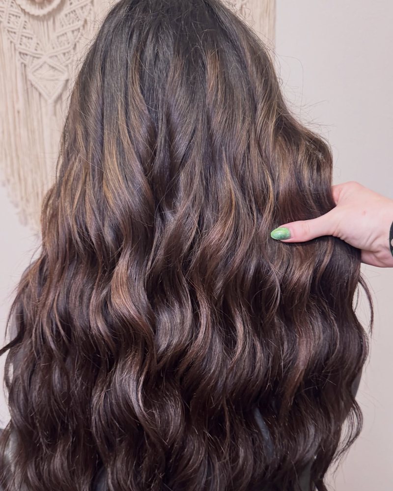 Long, full brunette waves after two rows of 24 inch sew-in weft extensions by an extension-certified stylist in Auburn CA.